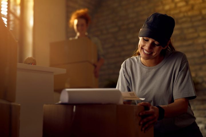 happy-female-courier-preparing-package-delivery-while-working-office_1_optimized_2000